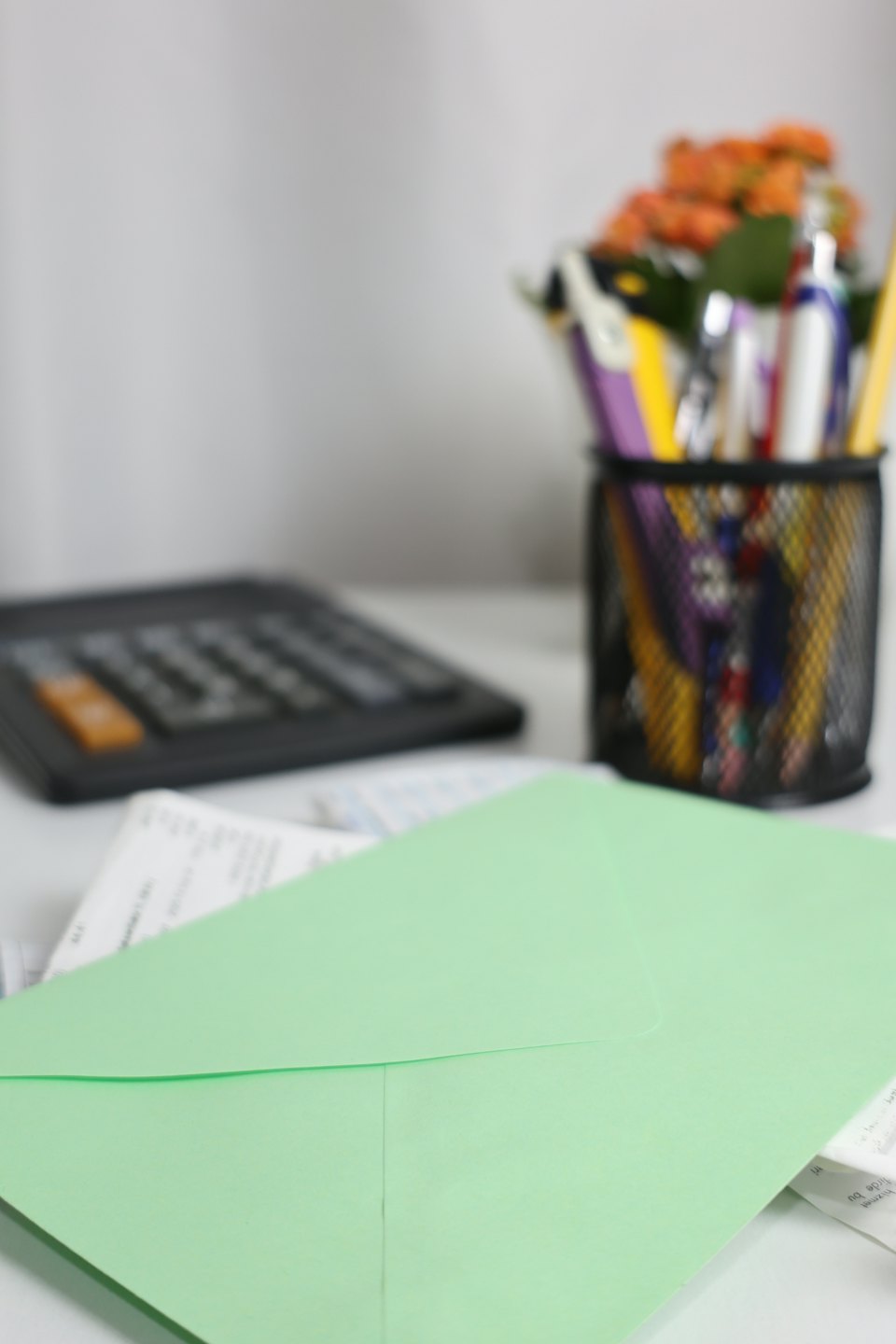 Une enveloppe vert clair posée sur des reçus sur un bureau blanc.