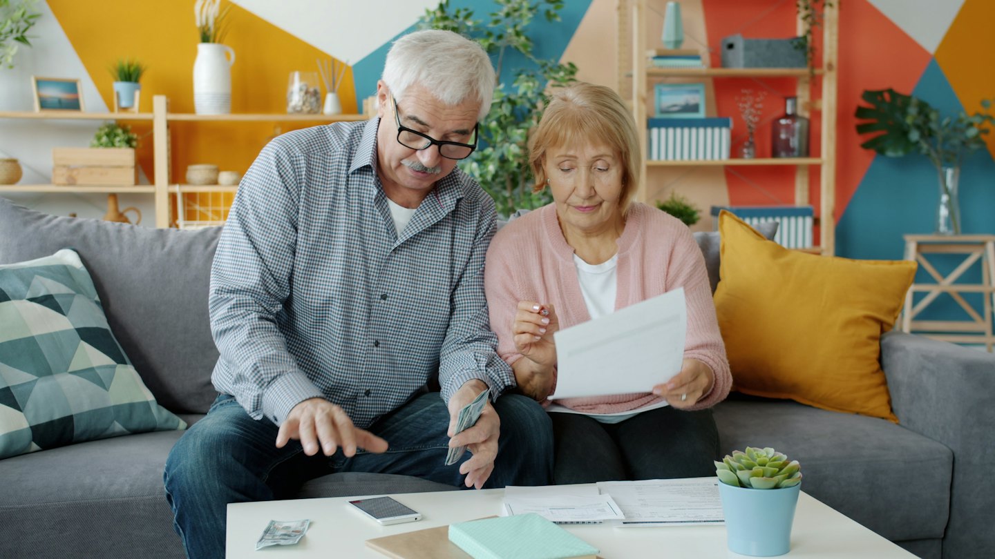 Couple âgé gérant leurs finances à une table basse.